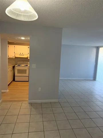 a view of a refrigerator in an empty room and a window