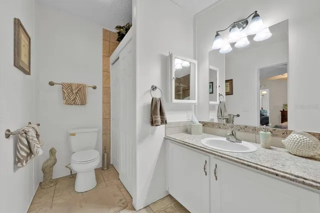 a bathroom with a granite countertop sink a toilet and a mirror