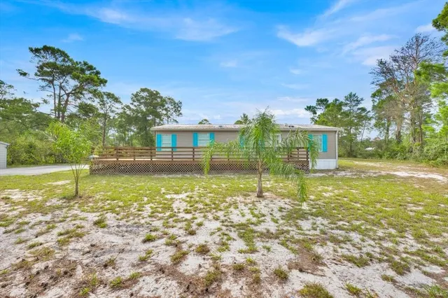 a view of a house with a yard and large tree