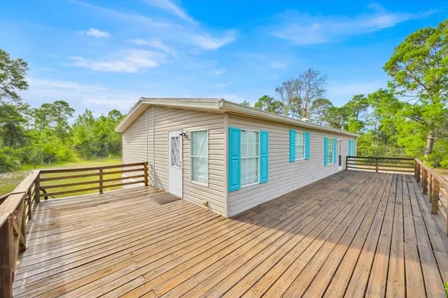 a view of a house with wooden floor next to a yard