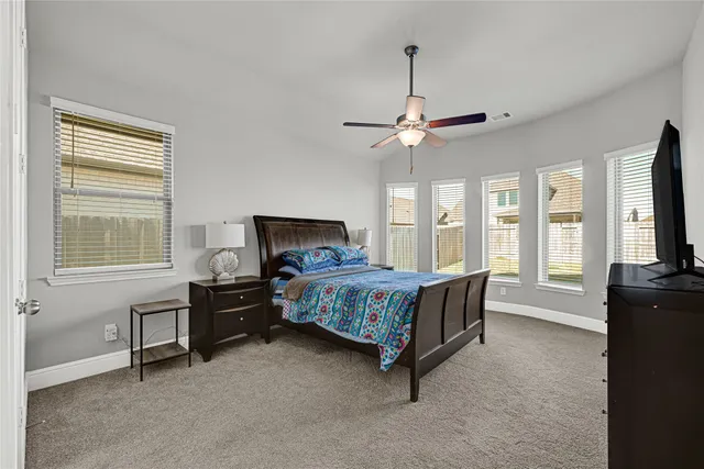 a bedroom with a bed and a flat tv screen on a dresser