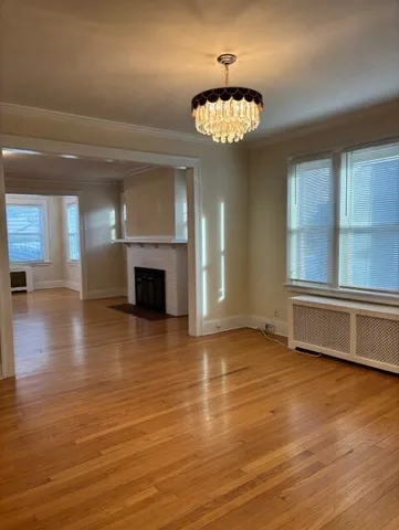 an empty room with wooden floor chandelier and windows