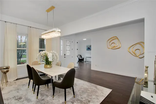 a view of a dining room and livingroom with furniture wooden floor a rug a potted plant and a chandelier