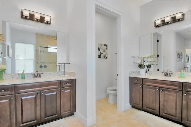 a spacious bathroom with a granite countertop sink a toilet and a mirror