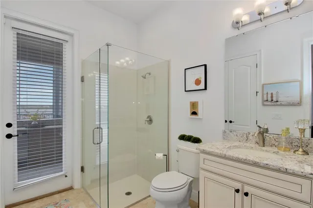 a bathroom with a granite countertop sink a toilet a shower and a mirror