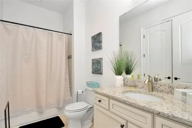 a bathroom with a granite countertop sink a toilet and a mirror