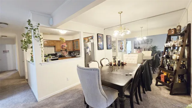 a dining room with stainless steel appliances furniture a chandelier and kitchen view