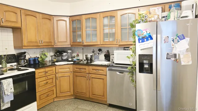 a kitchen with stainless steel appliances granite countertop a refrigerator a sink and white cabinets