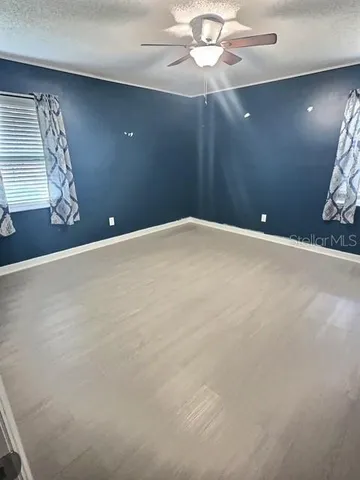 an empty room with windows and fan