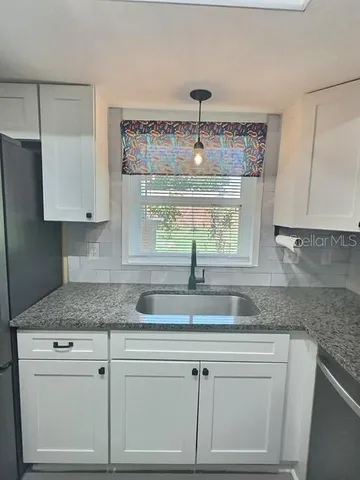a kitchen with granite countertop white cabinets and a sink