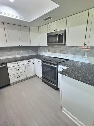 a kitchen with granite countertop a sink cabinets and stainless steel appliances