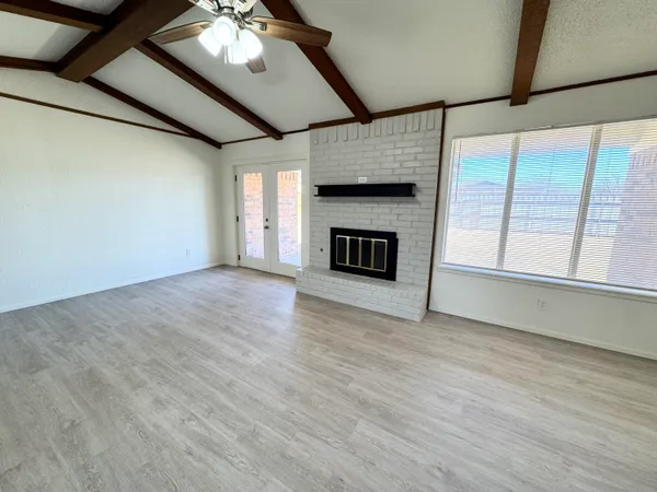 an empty room with windows fireplace and sink