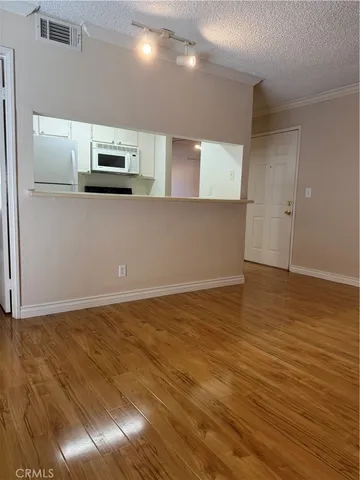 a view of kitchen with stainless steel appliances wooden floor and cabinets