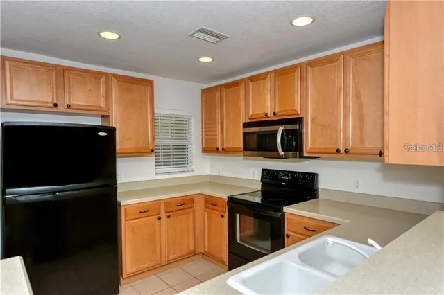a kitchen with granite countertop a refrigerator and a stove top oven