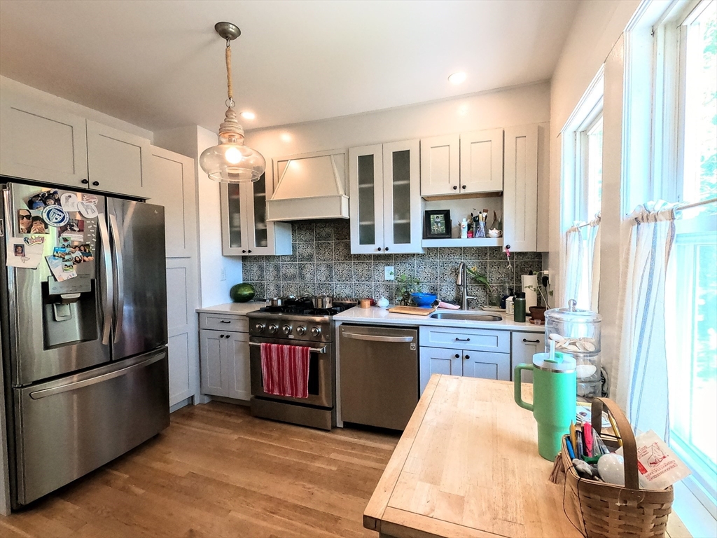 12 Searle Road, Unit 12 Boston, MA 02132 - Photo 5 of 35 a kitchen with stainless steel appliances granite countertop a refrigerator a stove a sink dishwasher and white cabinets with wooden floor
