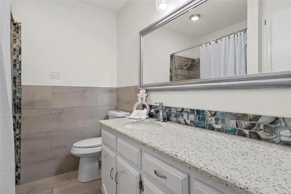 a bathroom with a granite countertop sink and a toilet