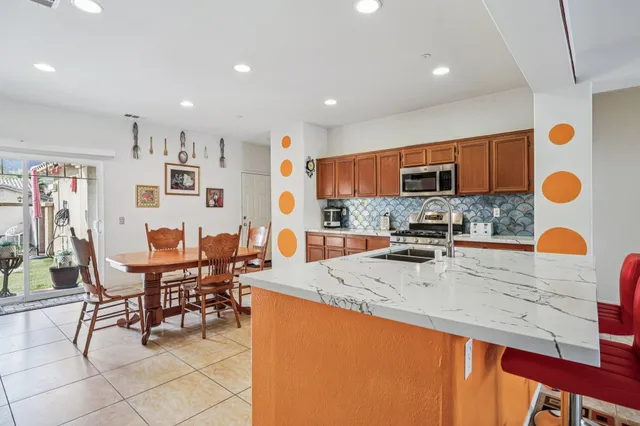 a dining area with stainless steel appliances kitchen island granite countertop a dining table and chairs
