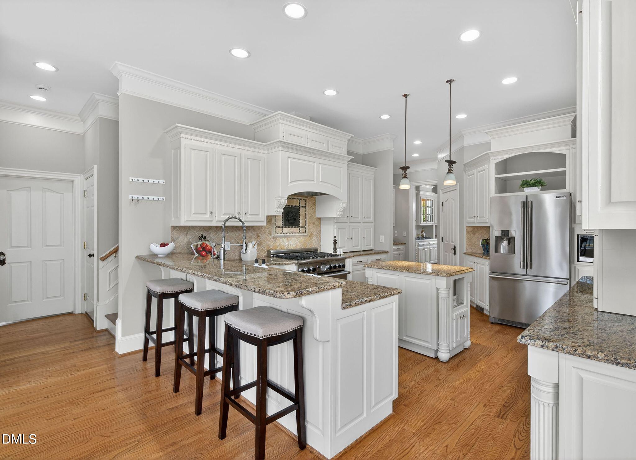 1609 Holland Road Fuquay-Varina, NC 27526 - Photo 18 of 79 a kitchen with stainless steel appliances granite countertop a table chairs sink refrigerator and microwave