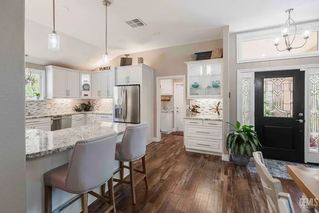 a kitchen with stainless steel appliances a dining table chairs refrigerator and cabinets