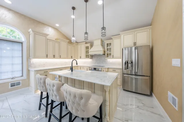 a kitchen with stainless steel appliances granite countertop a sink a stove a refrigerator and chairs