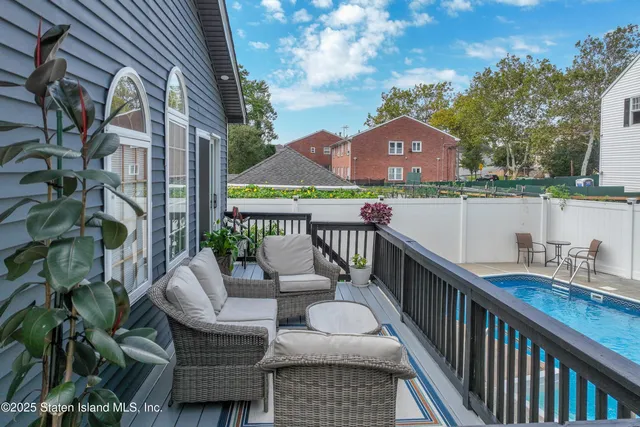a balcony of a house with wooden floor outdoor seating and barbeque oven