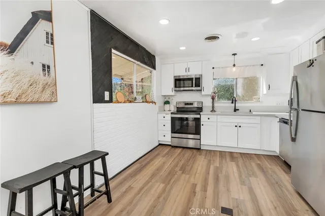 a kitchen with cabinets stainless steel appliances a sink and a window