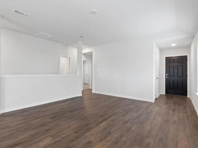 a view of an empty room with wooden floor