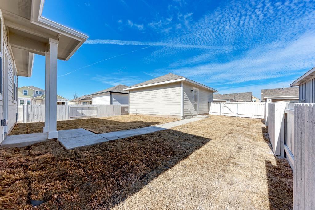 1209 Goforth Road Kyle, TX 78640 - Photo 29 of 32 A spacious backyard with mature grass and privacy fencing offers an ideal space for outdoor enjoyment.