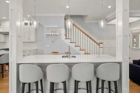 a kitchen with a dining table chairs and white cabinets