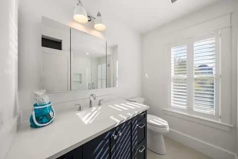 a bathroom with a granite countertop sink a toilet and a mirror