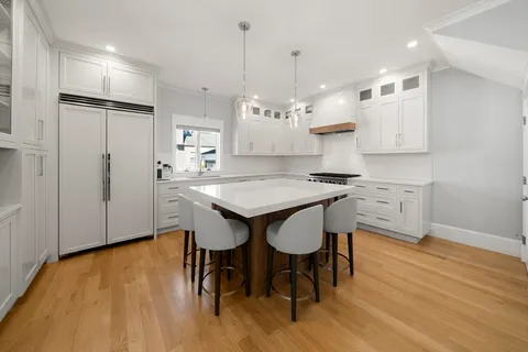 a kitchen with kitchen island a dining table chairs sink and stove
