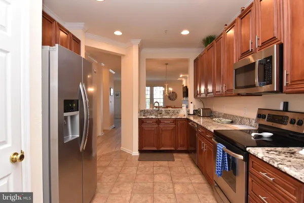 a kitchen with stainless steel appliances granite countertop a refrigerator a stove a sink and a microwave