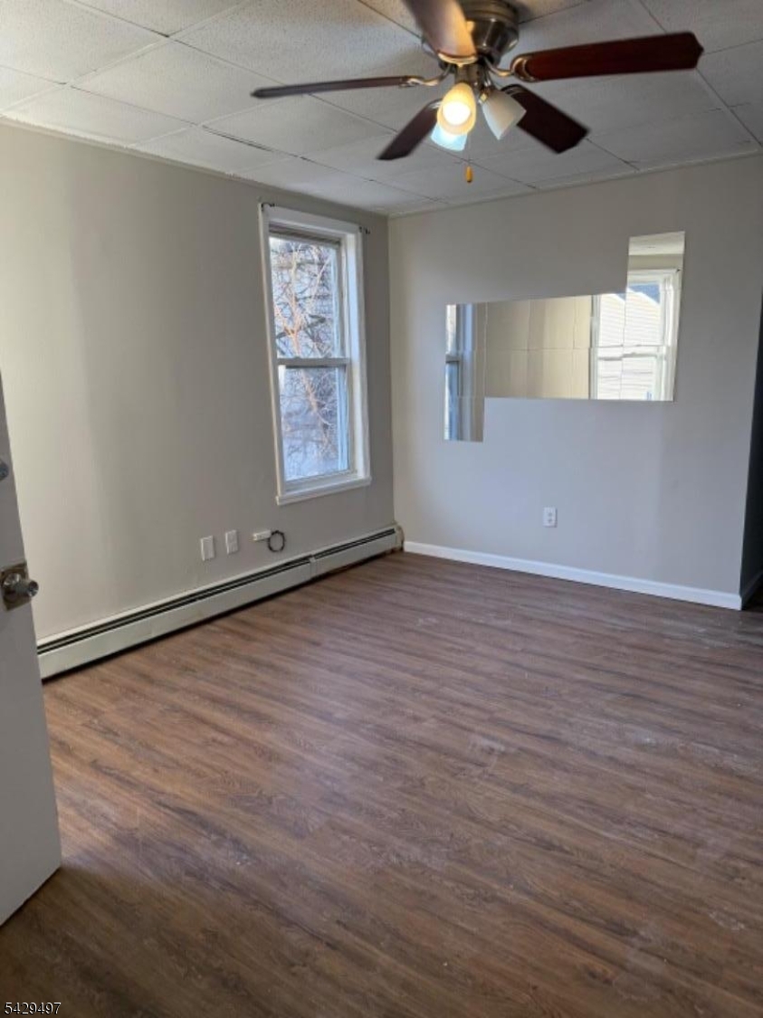 85 Holsman Street Paterson, NJ 07522 - Photo 5 of 20 an empty room with wooden floor chandelier fan and windows