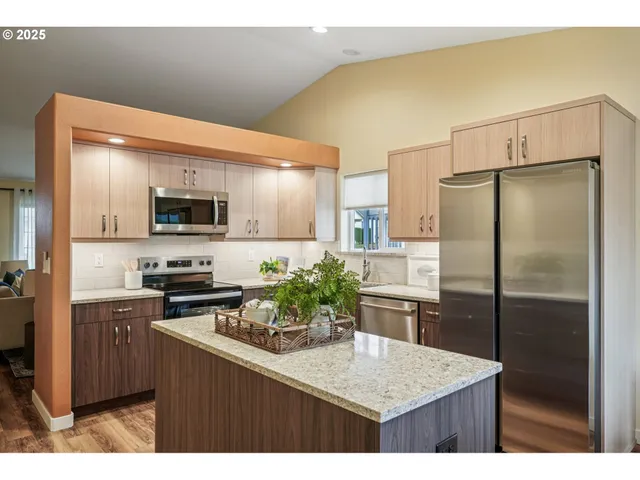 a kitchen with kitchen island a counter top space cabinets and stainless steel appliances