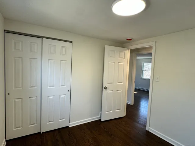 a view of an empty room with wooden floor and closet