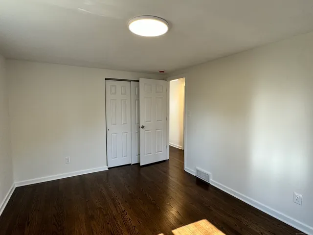 an empty room with wooden floor and window