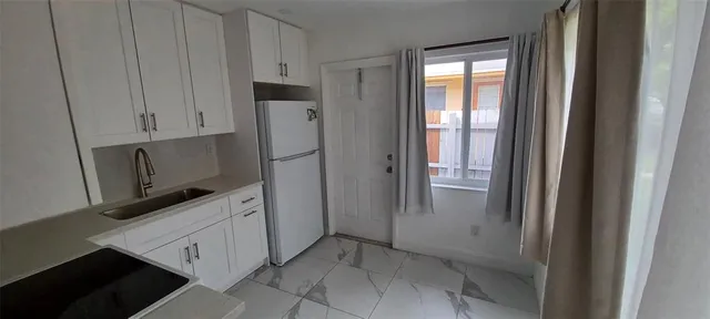 a kitchen with white cabinets and refrigerator