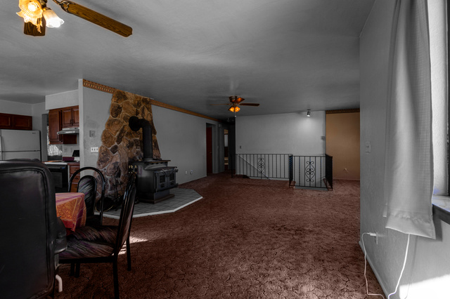 1208 East Tidwell Road Loa, UT 84747 - Photo 19 of 40 Carpeted living room with a wood stove and a ceiling fan