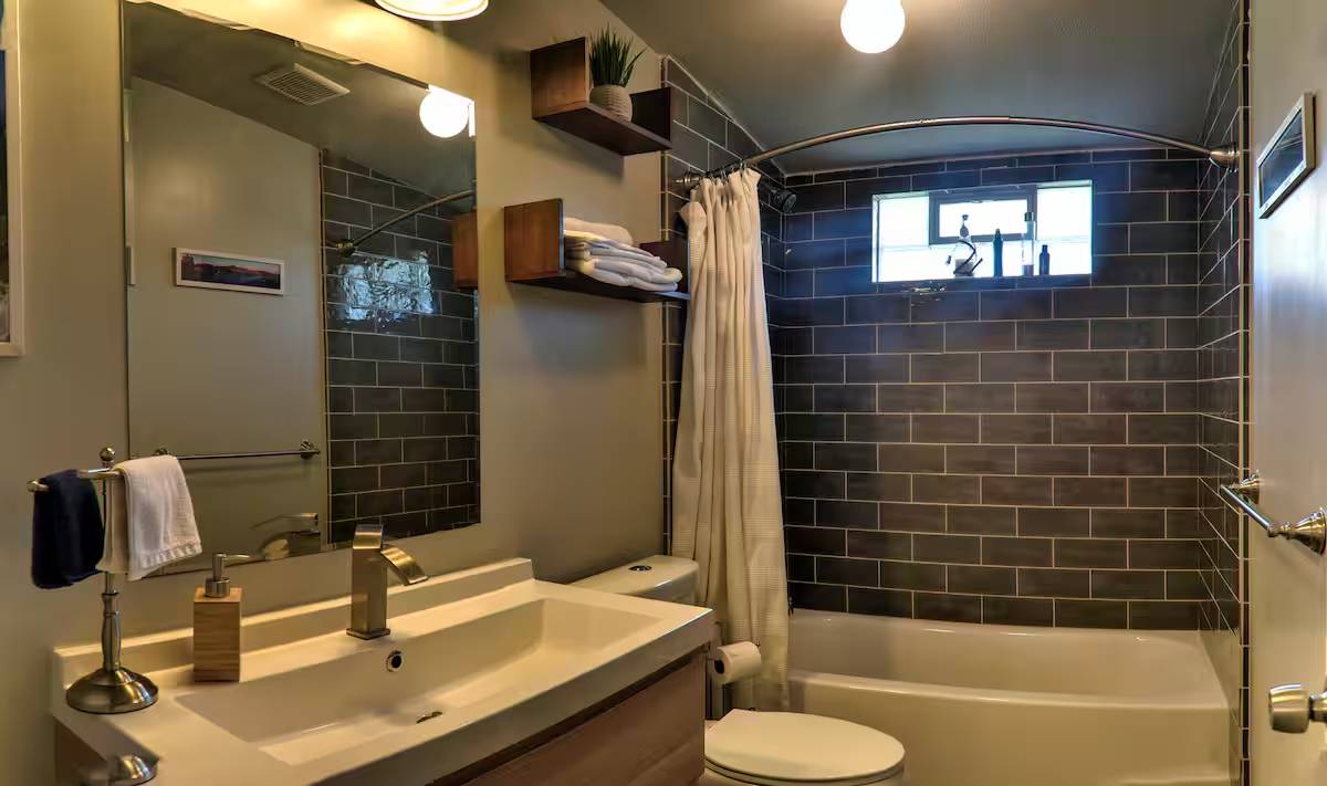 8807 High Valley Road Austin, TX 78737 - Photo 7 of 22 A well-appointed bathroom with dark subway tile and a modern vanity, offering comfort and functionality.