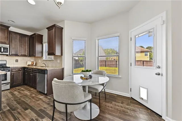 a kitchen with stainless steel appliances granite countertop a stove a refrigerator a sink dishwasher a dining table and chairs with wooden floor