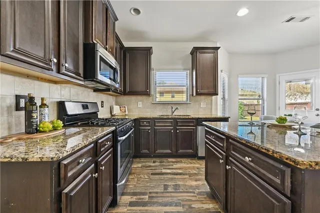 a kitchen with stainless steel appliances granite countertop a stove and a sink