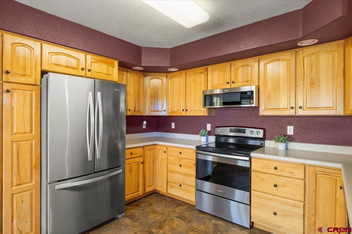 1600 Arland Road Montrose, CO 81401 - Photo 11 of 26 a kitchen with granite countertop a refrigerator stove and cabinets