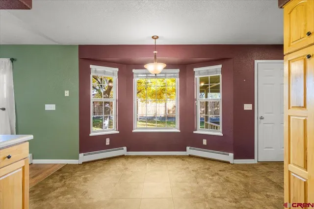 a view of an empty room with window and chandelier
