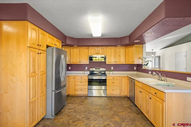 a kitchen with stainless steel appliances granite countertop a refrigerator a sink dishwasher a stove and a dining table with wooden cabinet