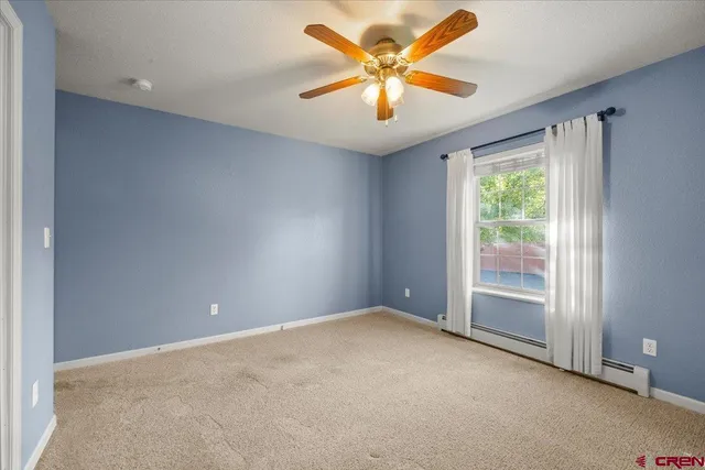 an empty room with a chandelier fan and windows
