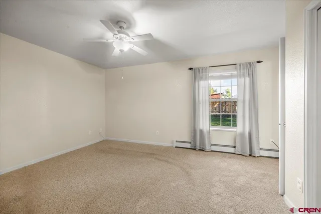 an empty room with chandelier fan and windows