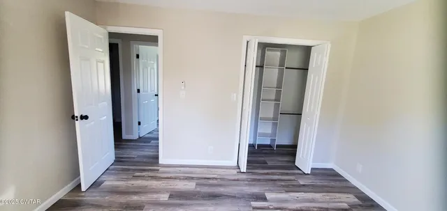 a view of a hallway with wooden floor and closet