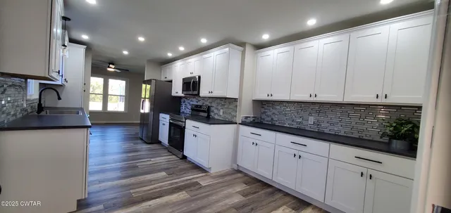 a kitchen with granite countertop white cabinets and white appliances