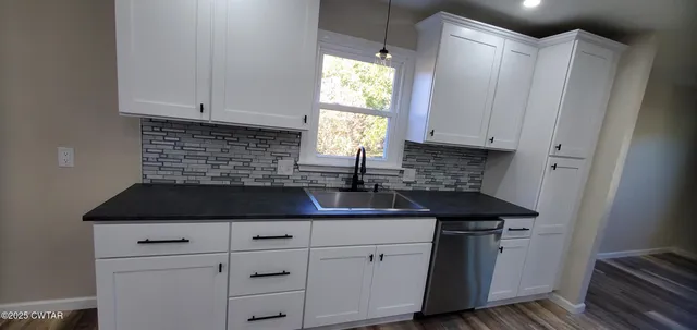 a kitchen with granite countertop white cabinets and a sink
