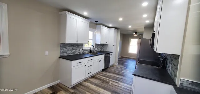 a kitchen with granite countertop a sink stove and cabinets